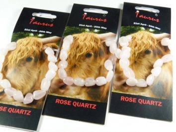Trzy bransoletki z różowego kwarcu na kartach z wizerunkiem byka i napisem "Taurus".