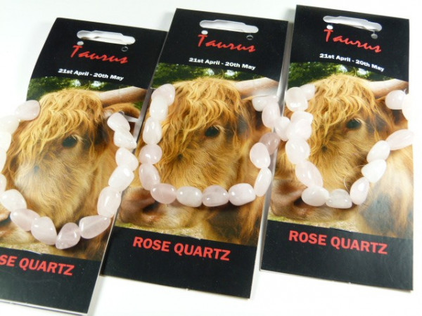 Trzy bransoletki z różowego kwarcu na kartach z wizerunkiem byka i napisem "Taurus".