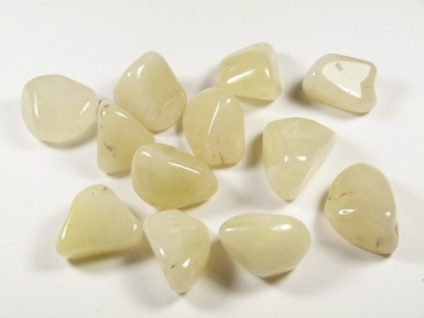 Kilka wypolerowanych, jasnokremowych kamieni leży na białym tle.