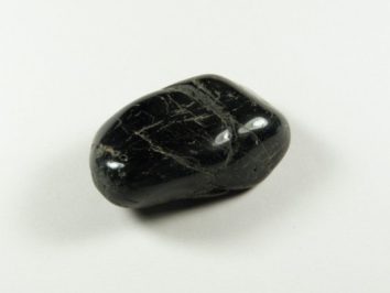 Czarny, wypolerowany kamień na białym tle, widoczny z góry.