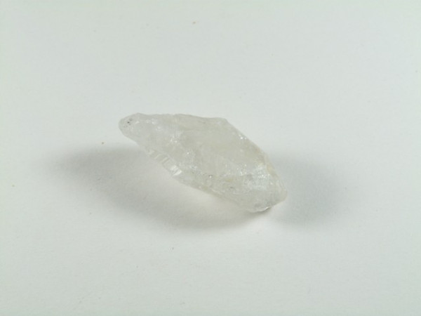 Przezroczysty kryształ kwarcu leżący na białym tle.
