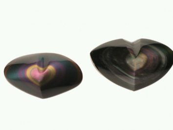 Dwa polerowane kamienie obsydianowe w kształcie serca na jasnym tle.