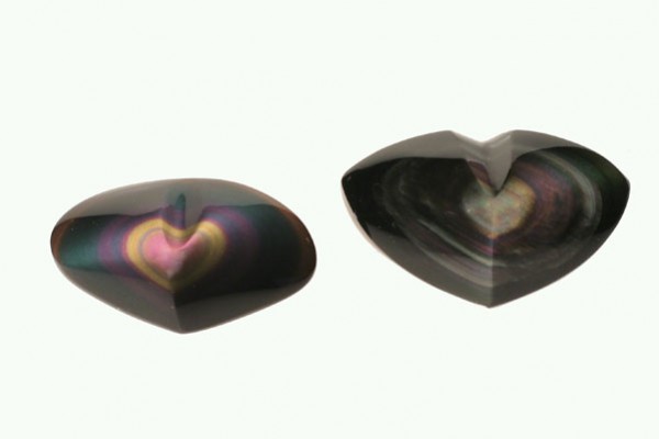 Dwa polerowane kamienie obsydianowe w kształcie serca na jasnym tle.