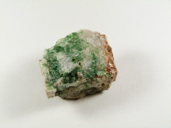 Biała skała z zielonymi i brązowymi smugami na jasnym tle.