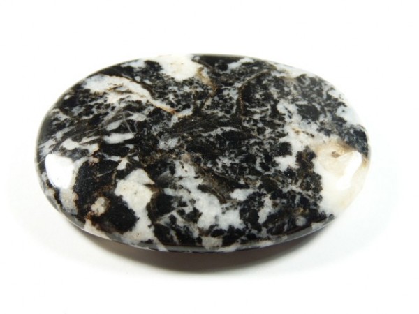 Owalny, polerowany kamień o czarno-białym, marmurkowym wzorze na białym tle.