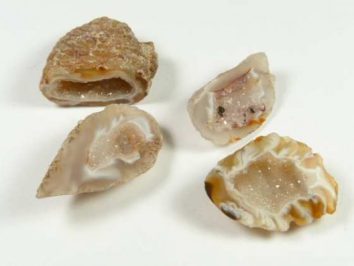 Agat mini geoda - kamień naturalny, surowy, nieszlifowany. Cztery przekrojone geody z widocznym błyszczącym wnętrzem, leżące na białym tle.