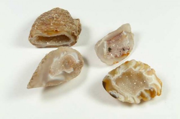 Agat mini geoda - kamień naturalny, surowy, nieszlifowany. Cztery przekrojone geody z widocznym błyszczącym wnętrzem, leżące na białym tle.