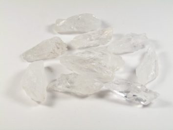 Kilka białych kryształów soli leży na białym tle.