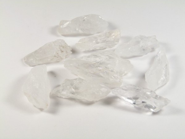 Kilka białych kryształów soli leży na białym tle.