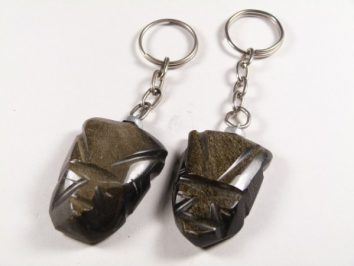 Dwa breloczki z kamiennymi zawieszkami w kształcie głowy Moai, leżące na białym tle.