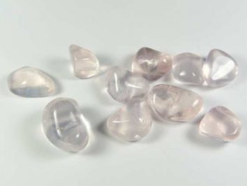 Dziesięć polerowanych kamieni różowego kwarcu leży na białym tle.