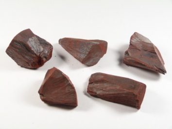 Pięć kawałków czerwonej rudy żelaza (hematytu) na białym tle.
