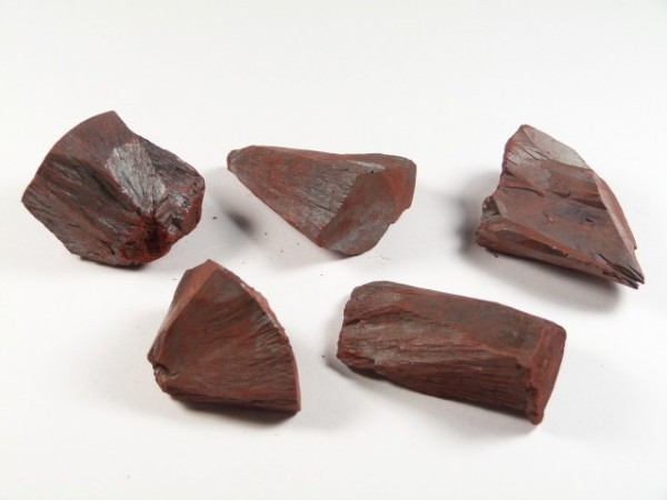 Pięć kawałków czerwonej rudy żelaza (hematytu) na białym tle.