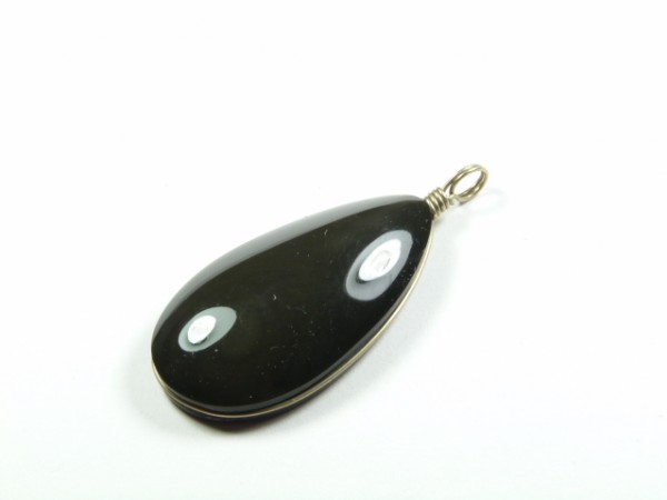 Czarny wisior z oczkami, w kształcie łzy, z metalowym uchwytem na biały tle.