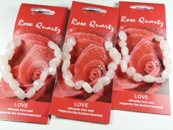 Trzy bransoletki z różowego kwarcu na czerwonych opakowaniach z napisem "Rose Quartz".