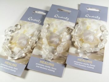 Trzy bransoletki z kryształu górskiego na kartach z napisem "Healing" i opisem w języku angielskim.
