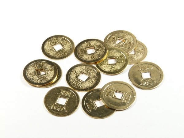 Kilka chińskich monet z kwadratowym otworem pośrodku leży na białym tle.