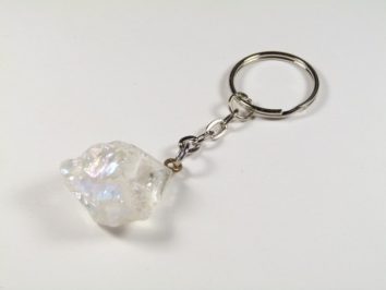 Brelok z przypiętym przezroczystym kryształem na białym tle.