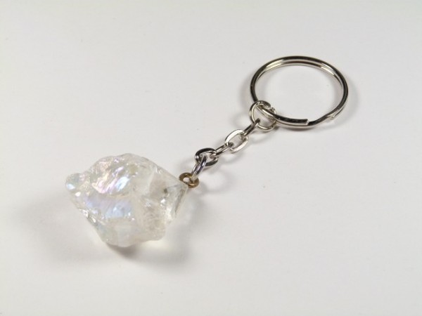 Brelok z przypiętym przezroczystym kryształem na białym tle.
