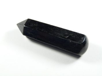 Czarny turmalin różdżka obelisk. Czarny, błyszczący kryształ o wydłużonym, szlifowanym kształcie na białym tle.