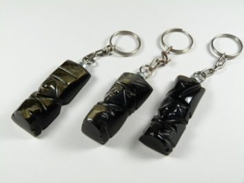 Trzy breloki z czarnymi figurkami ustawione na białym tle.