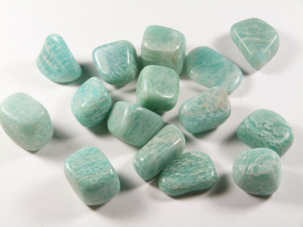 Kilka oszlifowanych, jasnozielonych kamieni leży na białym tle.