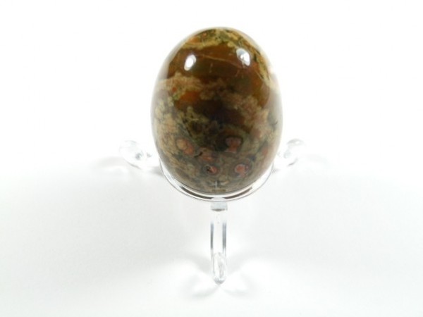 Jajko riolit szlifowany. Polerowany kamień w kształcie jaja, ustawiony na przezroczystej podstawce.