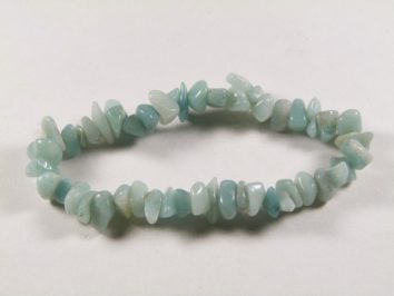 Bransoletka z nieregularnych, jasnoniebieskich kamieni na białym tle.