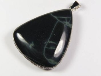 Czarny wisiorek z kamieniem o nieregularnych, jasnych żyłkach na białym tle.