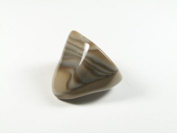 Krzemień pasiasty - kamień gładzony, polerowany, szlifowany i bębnowany w formie otoczaka. Wypolerowany, trójkątny kamień w odcieniach brązu na białym tle.