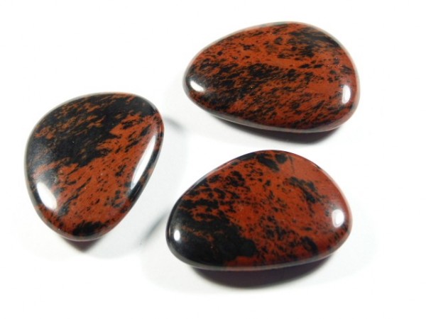 Obsydian brązowy szlifowany - płaski kamień. Trzy gładkie, czarno-czerwone kamienie leżą na białym tle.