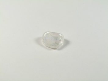 Przezroczysty, gładki kamień leży na białym tle.