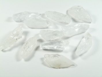 Kilka przezroczystych kryształów kwarcu leży na białym tle.