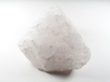 Duży, jasnoróżowy kryształ kwarcu na białym tle.