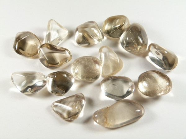Kilka oszlifowanych kamieni kwarcu dymnego ułożonych na białym tle.