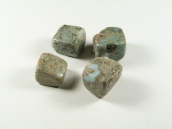 Cztery szare, nieregularne kamienie leżą obok siebie na białym tle.