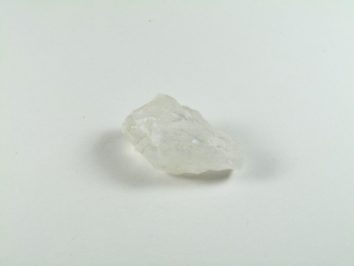 Przezroczysty kryształ leży na białym tle.