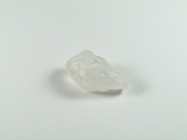 Przezroczysty kryształ leży na białym tle.