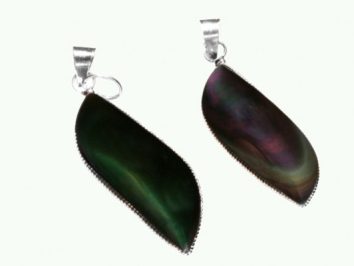 Dwa wisiorki z ciemnego, połyskującego kamienia na srebrnych zawieszkach, na jasnym tle.