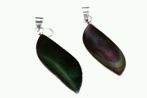 Dwa wisiorki z ciemnego, połyskującego kamienia na srebrnych zawieszkach, na jasnym tle.