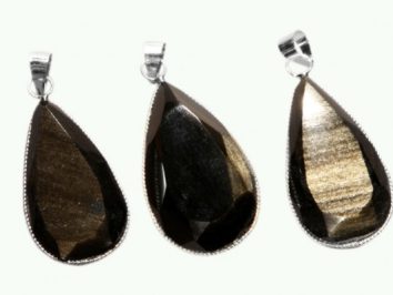 Trzy wiszące, fasetowane wisiorki z kamienia w kształcie kropli, z metalowymi oprawami.