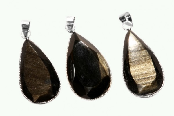 Trzy wiszące, fasetowane wisiorki z kamienia w kształcie kropli, z metalowymi oprawami.