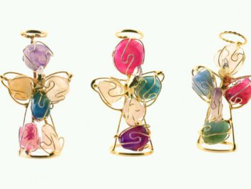 Trzy kolorowe aniołki z drutu i kamieni ozdobnych ustawione obok siebie na jasnym tle.