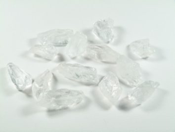 Kilka przezroczystych kryształków leży na białej powierzchni.