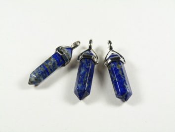 Trzy niebieskie kamienne wisiorki w kształcie kryształu leżące na białym tle.