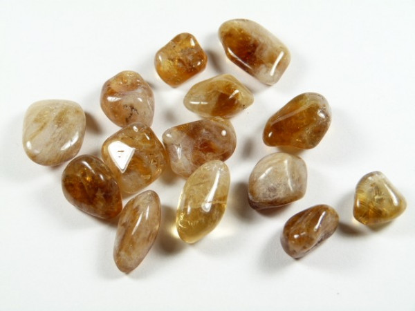 Kilka szlifowanych, brązowo-żółtych kamieni leży na białym tle.