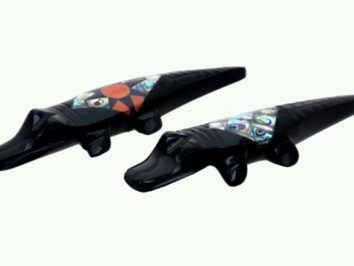 Dwa czarne figurki aligatorów z kolorowymi zdobieniami na grzbietach, na jasnym tle.