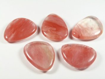Kwarc wiśniowy szlifowany - płaski kamień. Pięć polerowanych różowych kamieni leży na białym tle.