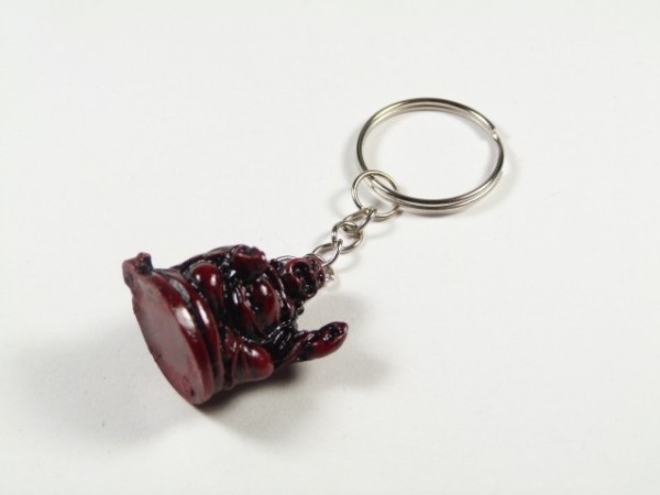 Breloczek z figurką siedzącego Buddy na białym tle.