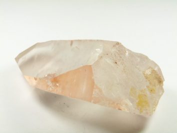 Przezroczysty kryształ kwarcu leży na białym tle.